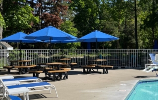 outdoor pool deck with lounge chairs and circular patio tables with umbrellas